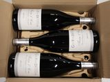 three bottles of wine are in a cardboard box on a table
