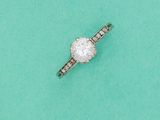 une bague en diamant posée sur un fond vert, avec un diamant au centre