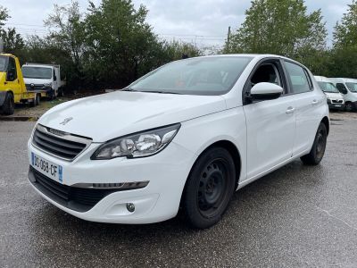 La voiture blanche est garée sur le parking, à côté d'autres voitures.