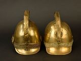 two gold helmets on top of each other on a black background