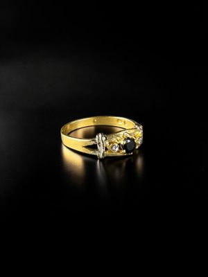 a yellow gold ring with two diamonds on a black background