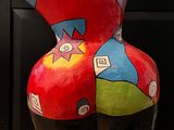a colorful sculpture of a vase on a black stand