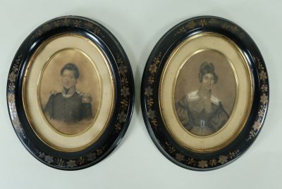 deux portraits encadrés représentant un homme et une femme, dans des tons de noir et d'or
