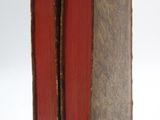 two red books sitting on top of each other on a white surface