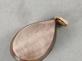 a close up of a gold pendant with a tear shaped pendant on it