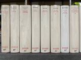 several white books are lined up on a shelf in a library