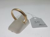 une bague en or posée à côté d'une étiquette sur une surface blanche
