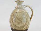 a brown and black vase on a white surface
