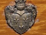 a metal plaque on a wooden cabinet that has a coat of arms on it