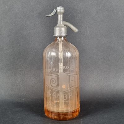 une bouteille en verre transparent munie d'une poignée métallique posée sur une surface grise