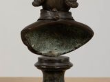 bronze bust of a boy with a hat on a pedestal
