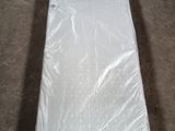 un matelas emballé dans du plastique, posé à même le sol
