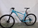 le vélo est bleu et la roue avant a des rayons noirs