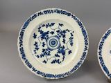 two blue and white plates with flowers and leaves on them