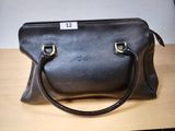 un sac à main en cuir noir posé sur une table, avec une étiquette de prix dessus