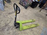 un chariot élévateur vert posé à même le sol dans un entrepôt