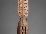 an image of a wooden sculpture on a stand on a gray background