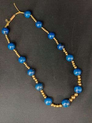 un collier de perles bleues et dorées sur un fond noir