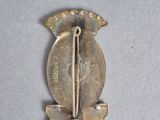 a picture of a silver pin with a sword and shield on it