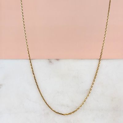 un collier à chaîne en or posé sur une surface en marbre