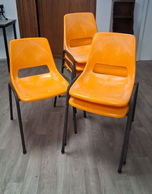 trois chaises en plastique orange posées sur un parquet en bois massif