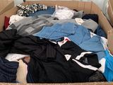 a cardboard box full of clothes that is sitting on the floor