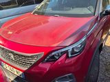Une voiture rouge est garée à côté d'autres voitures dans un parking.
