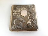 a silver cigarette case with a dragon design on it