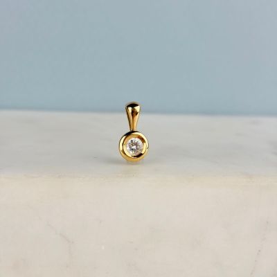 un pendentif en diamant posé sur une surface en marbre blanc