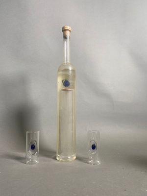 une bouteille d'alcool et deux verres à shot posés sur une table