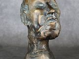sculpture en bronze représentant la tête d'un homme sur fond gris