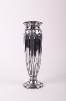 un vase en argent posé sur une surface blanche