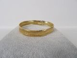 gros plan d'un bracelet en or sur une surface blanche