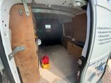 une camionnette blanche avec une porte en bois et un seau rouge à l'arrière