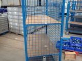 blue steel caged cart in a warehouse with pallets and boxes