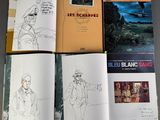several books with drawings and pictures of people on them sitting on a table