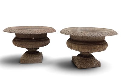 two stone vases sitting side by side on a white surface