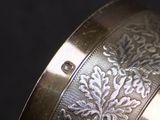 a close up of a silver cuff with a floral design on it