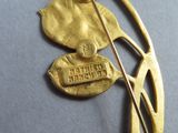 a gold brooch with a flower and a pin on it