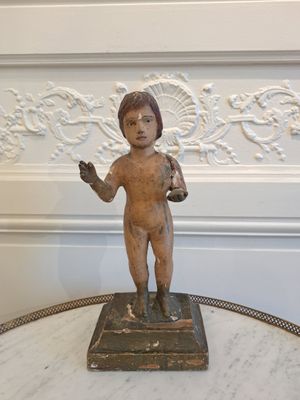une petite statue représentant un garçon, posée sur une table en marbre