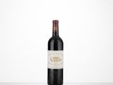 a bottle of wine sitting on top of a table next to a white wall