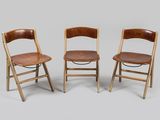 trois chaises pliantes en bois avec des assises en cuir marron sur fond gris