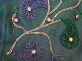 purple and green beaded flowers and leaves on a green jacket
