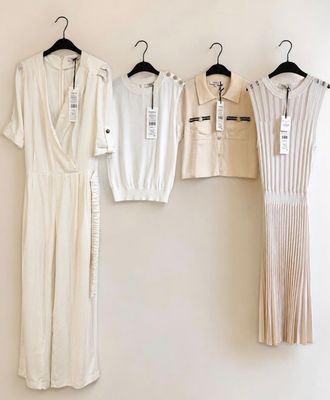 trois robes blanches accrochées à un mur, à côté d'un cintre noir