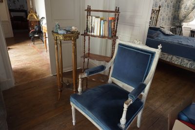 une chaise bleue et blanche dans une pièce où se trouve une bibliothèque