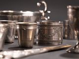 many silver cups and spoons sitting on a table