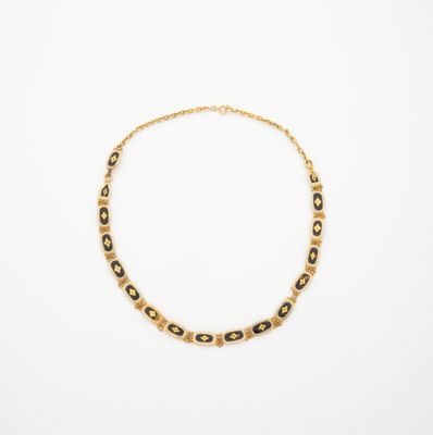 un collier en or orné de perles noires et blanches sur fond blanc