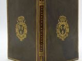 an old book with gold trim and a crown on the cover