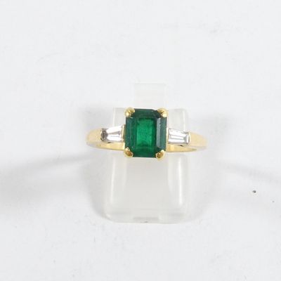 une bague en émeraude et diamants, ornée de diamants taille baguette sur un fond blanc