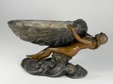 bronze sculpture of a winged boy on a rock with a large rock in the background